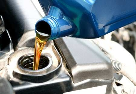 A Person Is Pouring Oil Into A Car Engine — Town Automatics 4WD & Mechanical in South Townsville, QLD