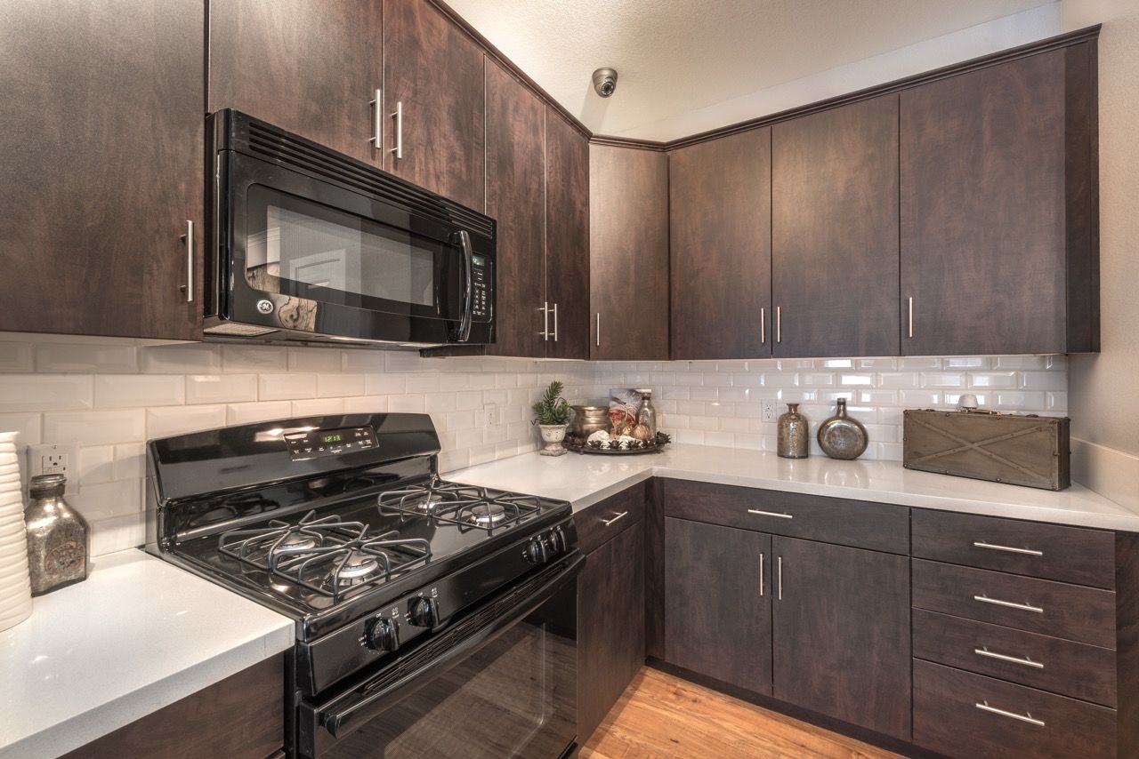 Modern kitchen with dark wood cabinets, white counters, and stainless steel appliances.