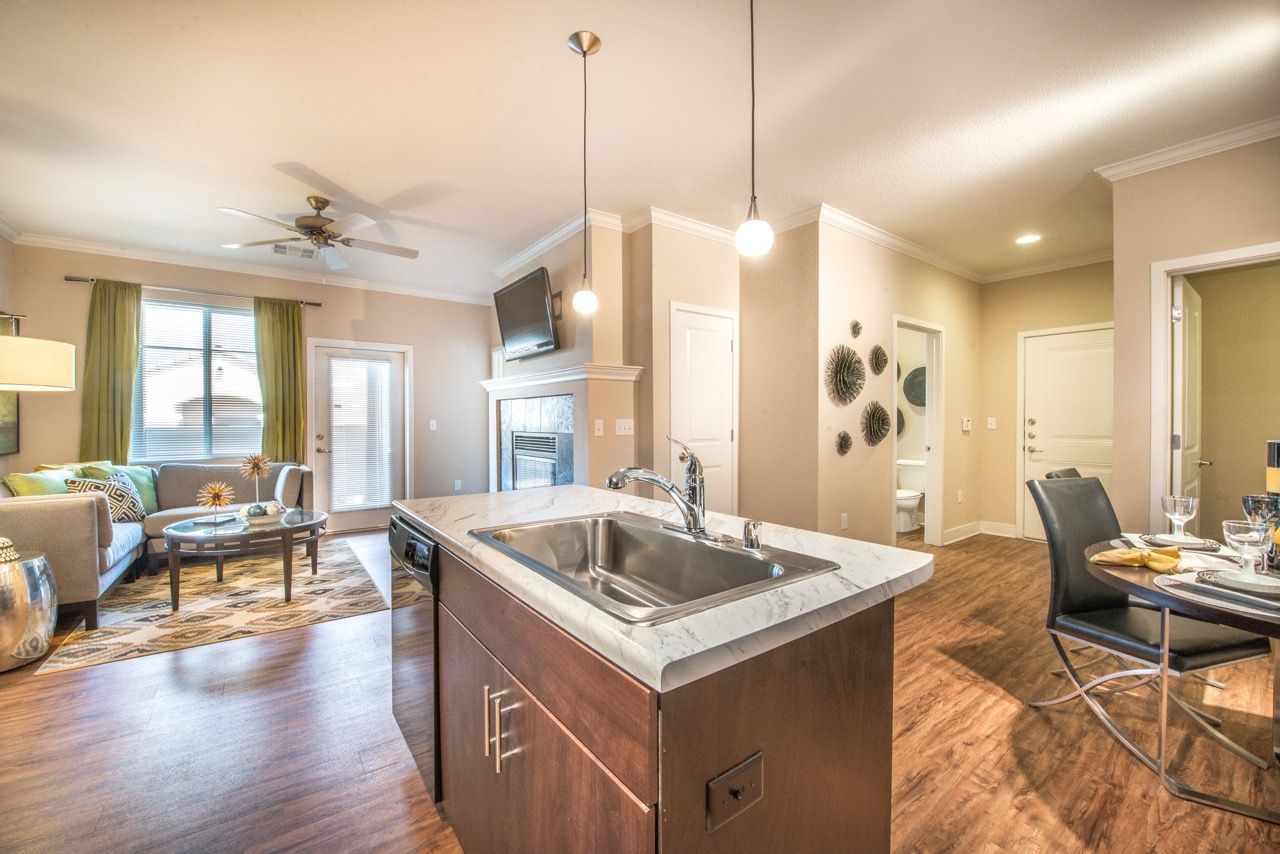 Open-concept kitchen with marble-topped island and adjacent living and dining areas.