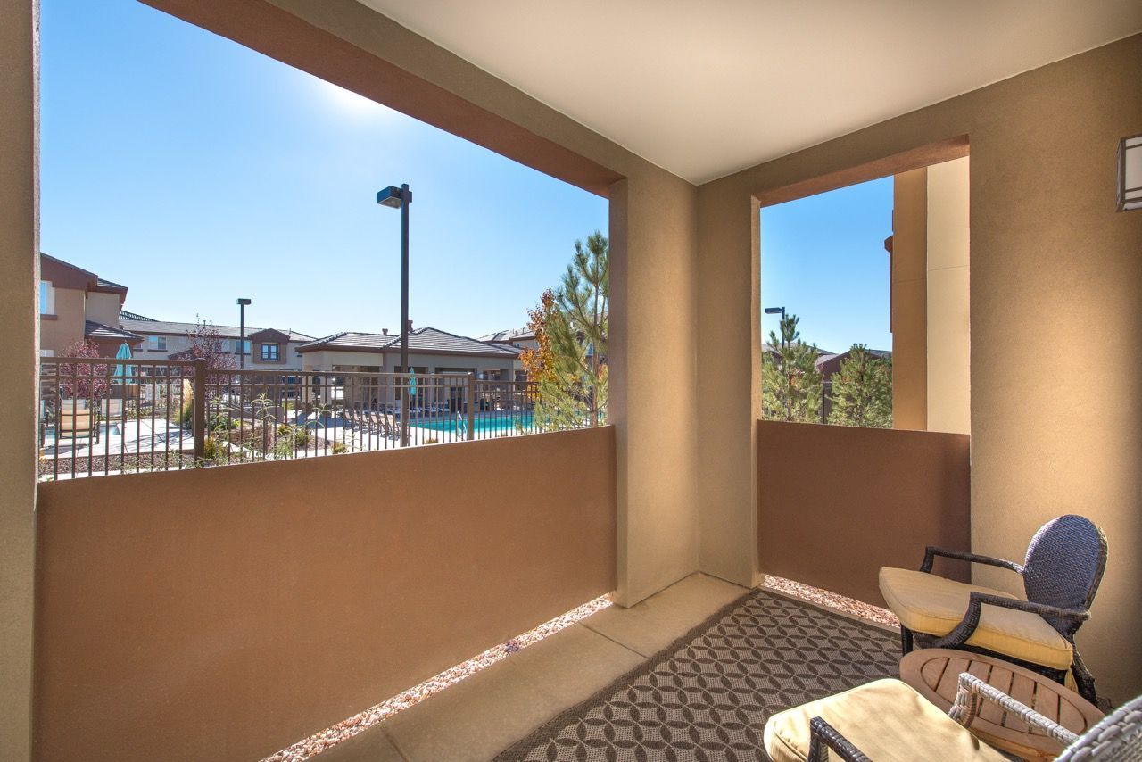 Balcony with wicker chairs overlooking the apartment pool area.