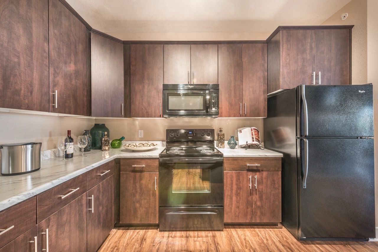 Modern kitchen with dark wood cabinets, stainless steel appliances, and marble-like countertops.