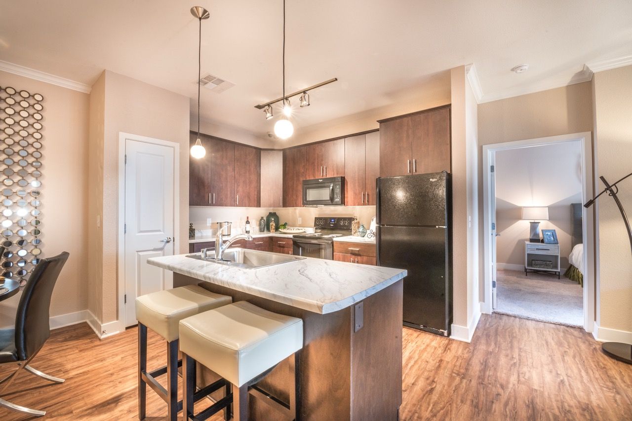 Open-concept kitchen with marble island, dark wood cabinets, and stainless steel appliances.