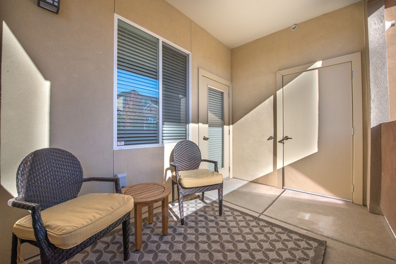 Outdoor patio with two wicker chairs and a small table on an apartment balcony.