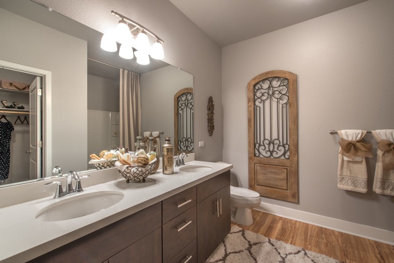 Bathroom with a double-sink vanity, large mirror, towels, and a decorative arched metal door.