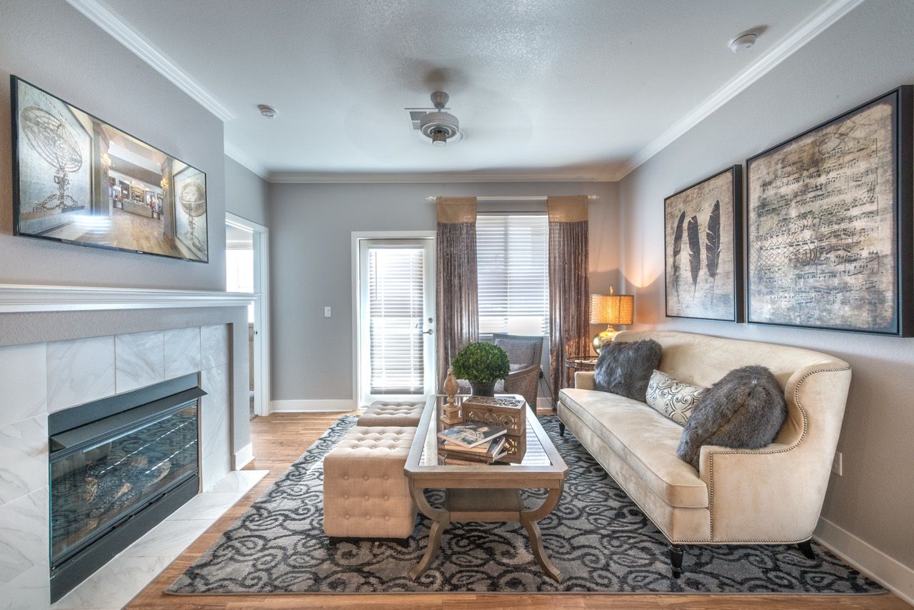 Interior living room in a modern apartment with a beige sofa, fireplace, and framed wall art.