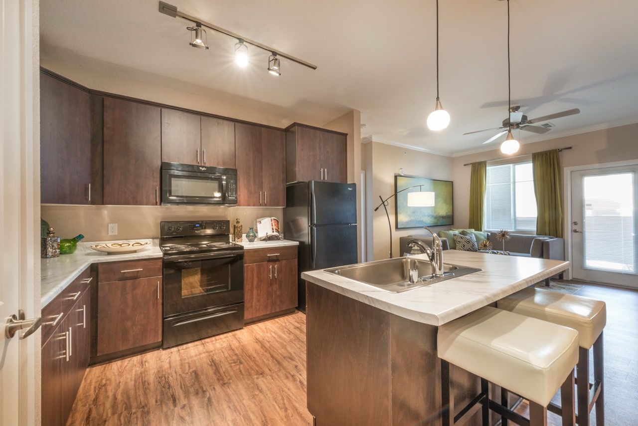 Modern kitchen with dark wood cabinets, stainless steel appliances, and an island with seating.