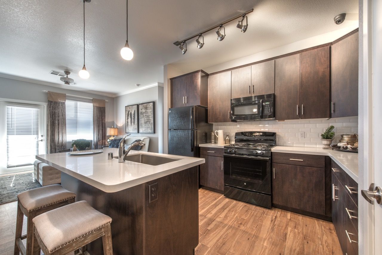 Open-concept kitchen with a large island, dark wood cabinets, and stainless steel appliances.