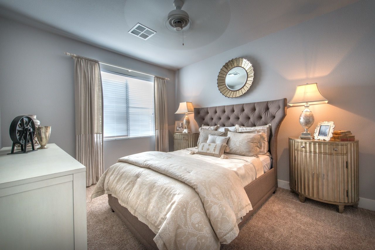 Bedroom in a modern apartment with a tufted headboard, nightstands, and curtains.