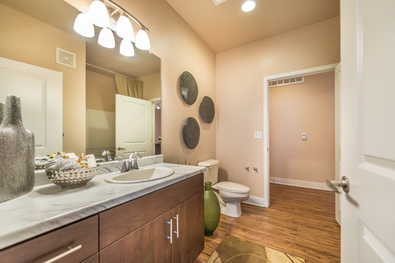 Bathroom with single-sink vanity, marble countertop, large mirror, and toilet.