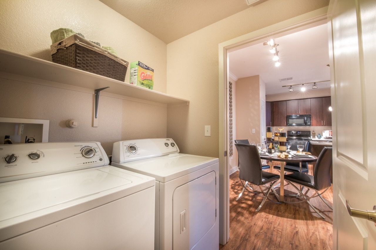 Laundry area with washer and dryer, shelving above, opening into the kitchen/dining space.