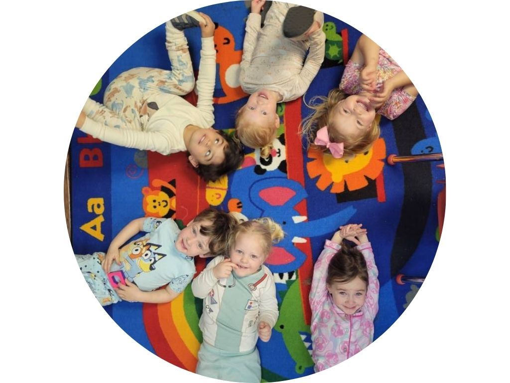 A group of children are sitting around a table in a circle.