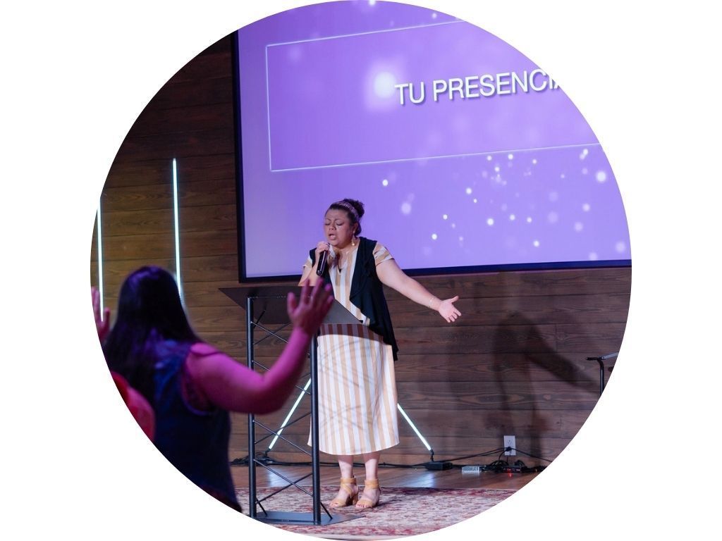 A group of people are standing in front of a large screen in a church.