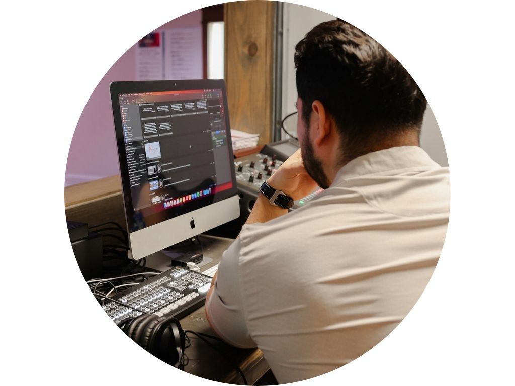 A man is sitting at a mixer in front of a crowd of people