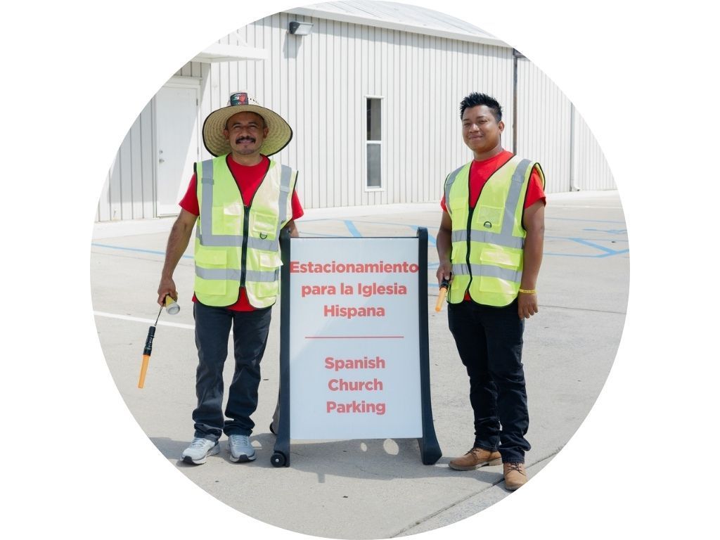 A man in a yellow shirt is walking through a parking lot