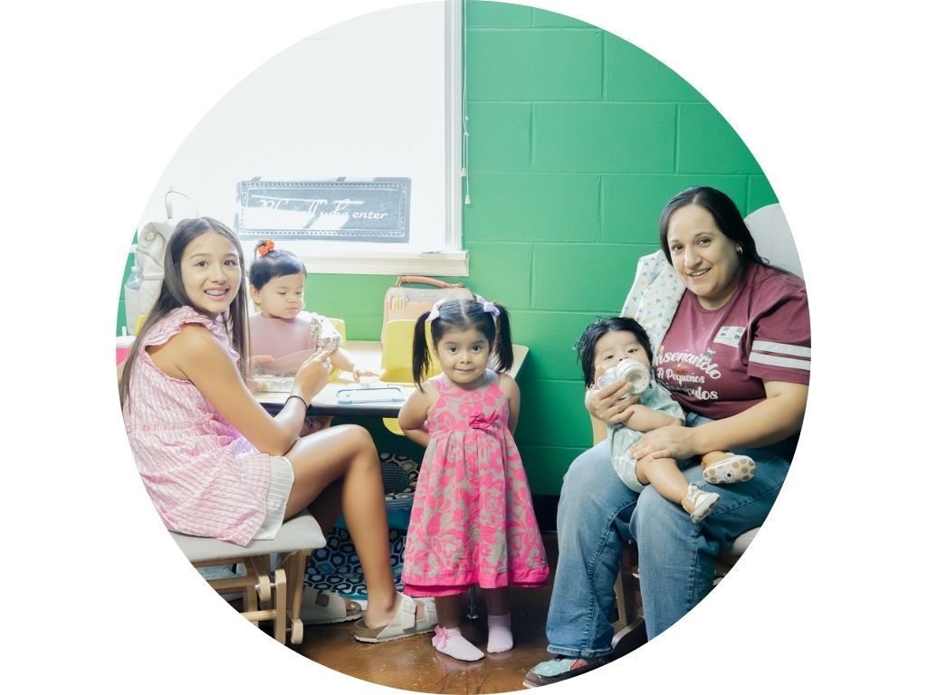 A woman is sitting in a chair holding two children.