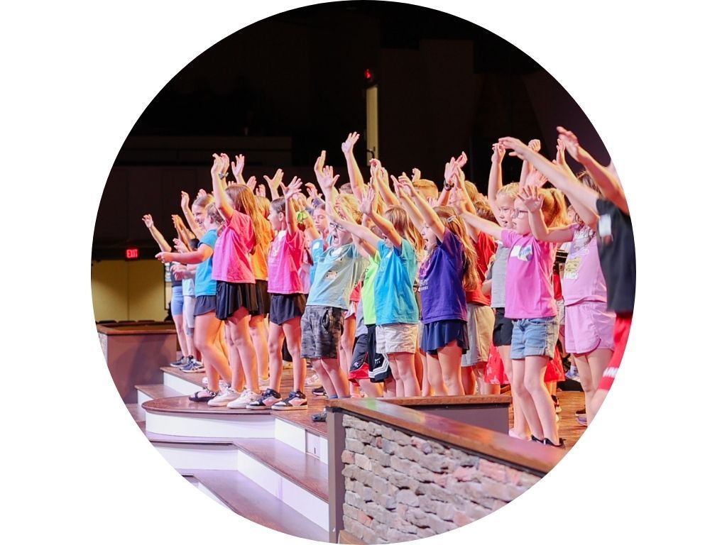 A group of people are sitting in a lecture hall raising their hands to answer a question.