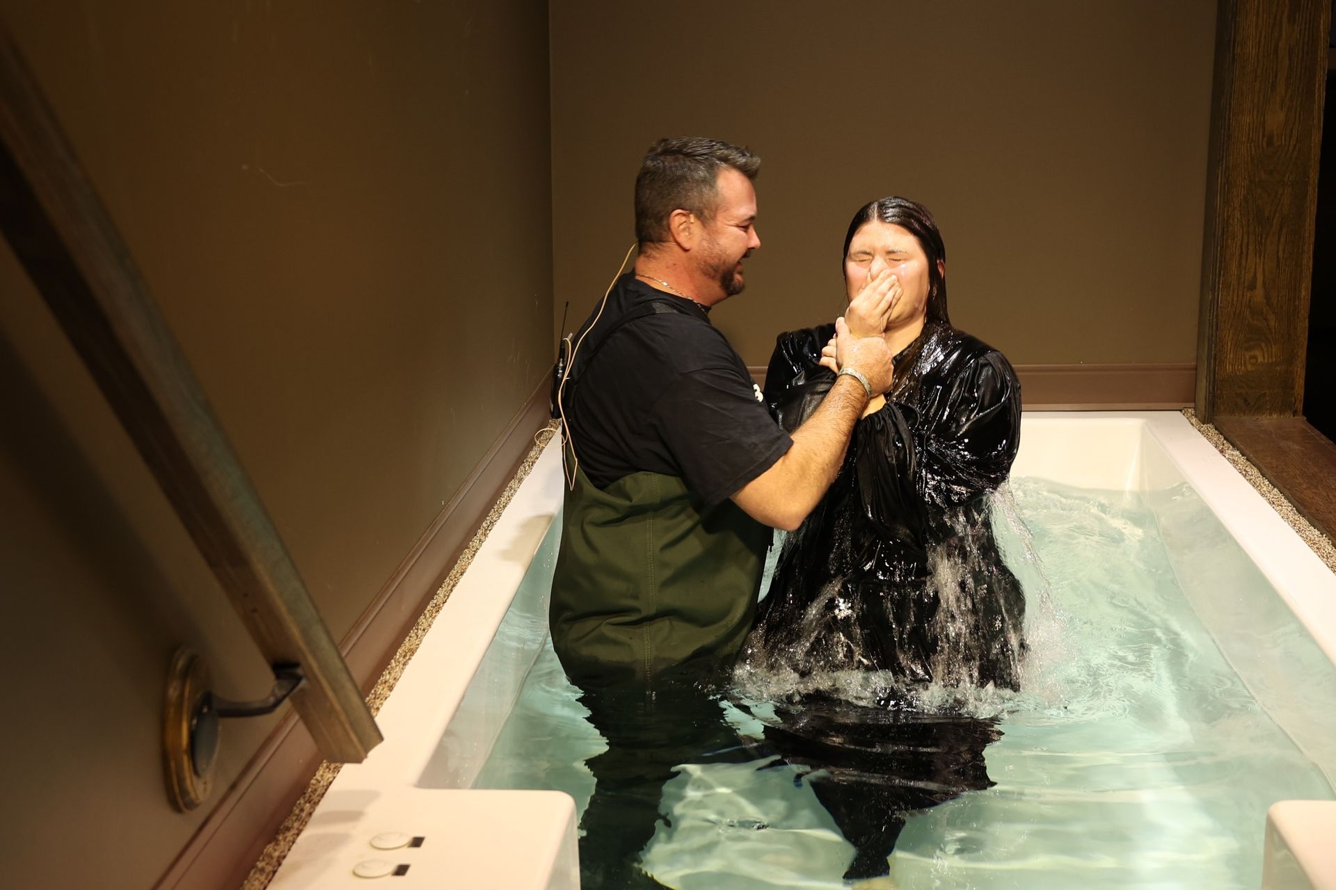 A man is baptizing a woman in a bathtub.