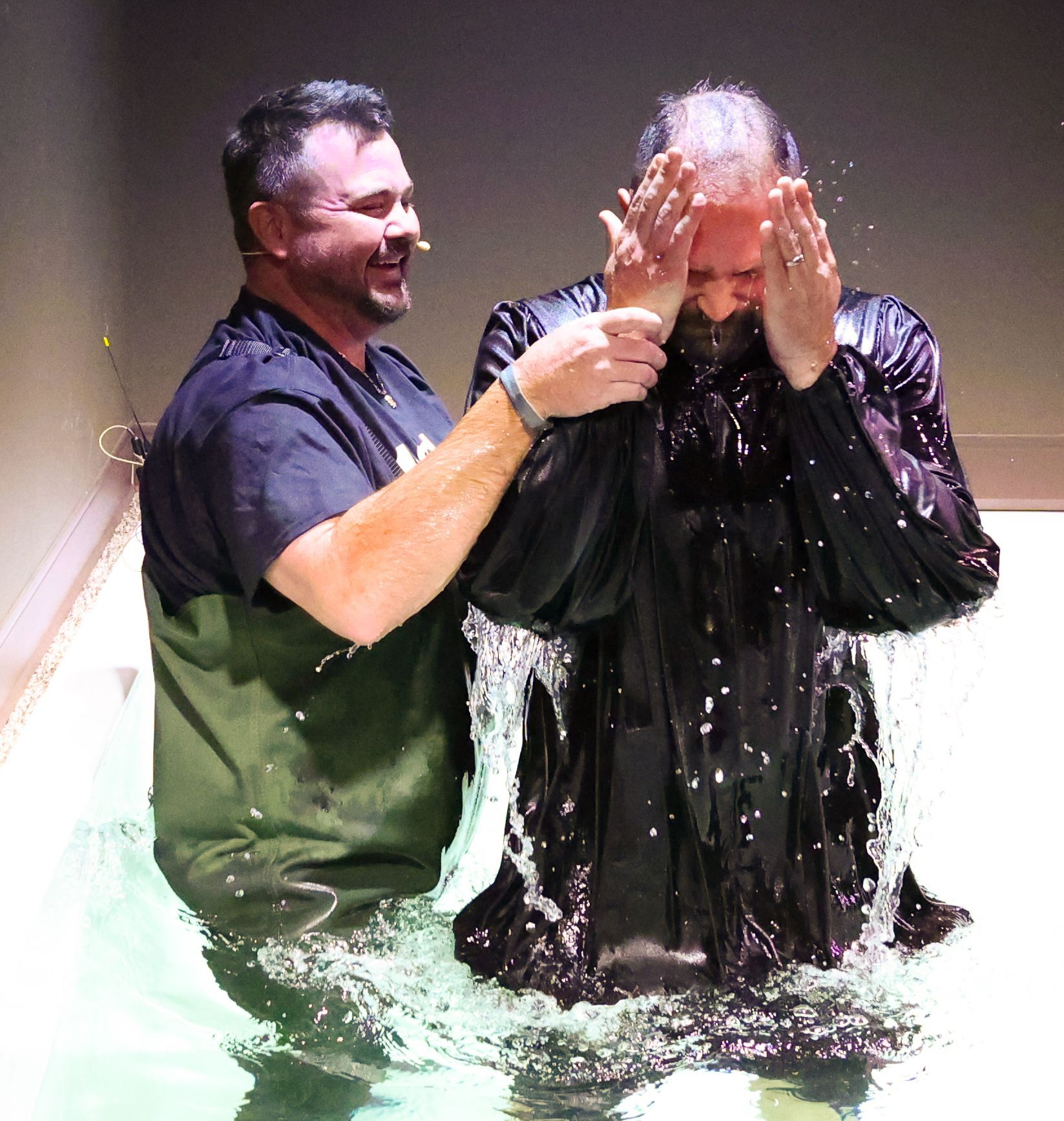 A man is being baptised by another man in the water