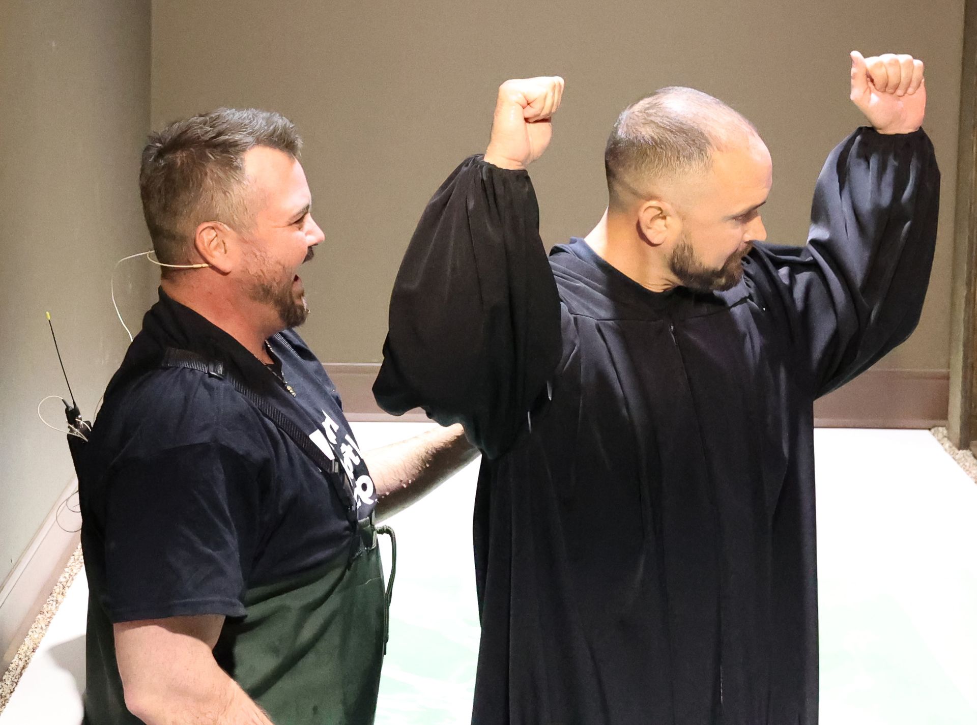 Two men are standing next to each other with their arms in the air.