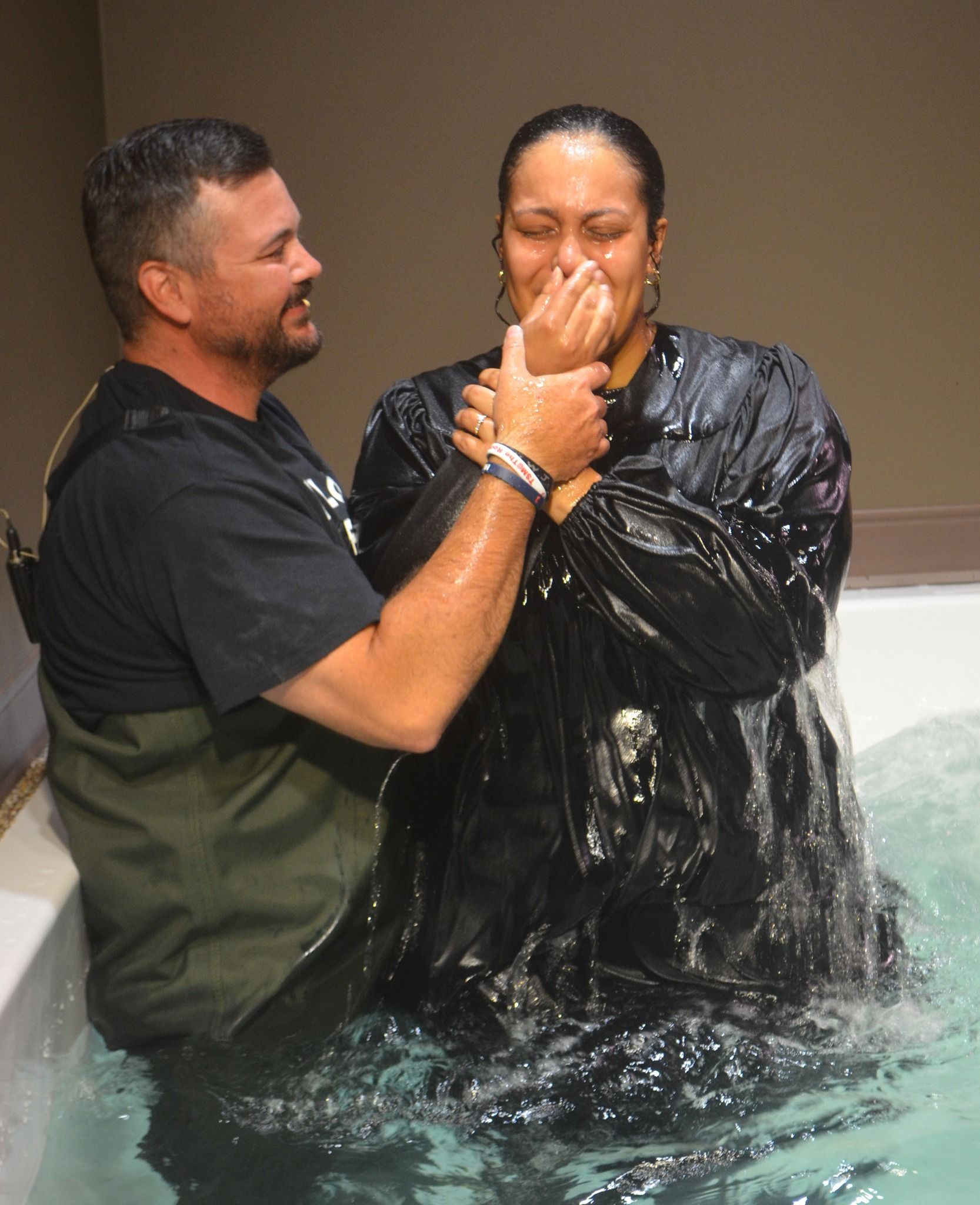 A man is baptizing a woman in the water