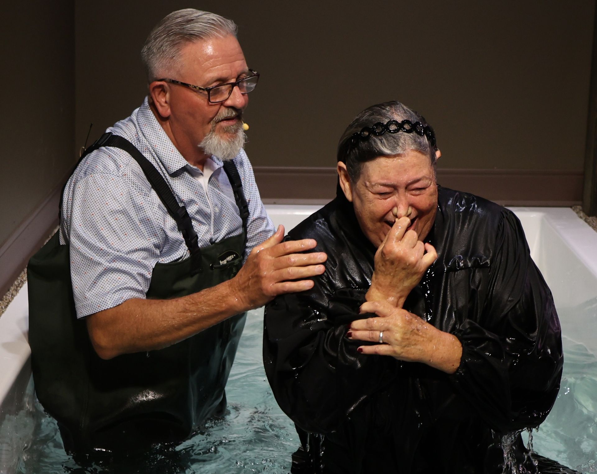 A man is standing next to a woman in a bathtub.