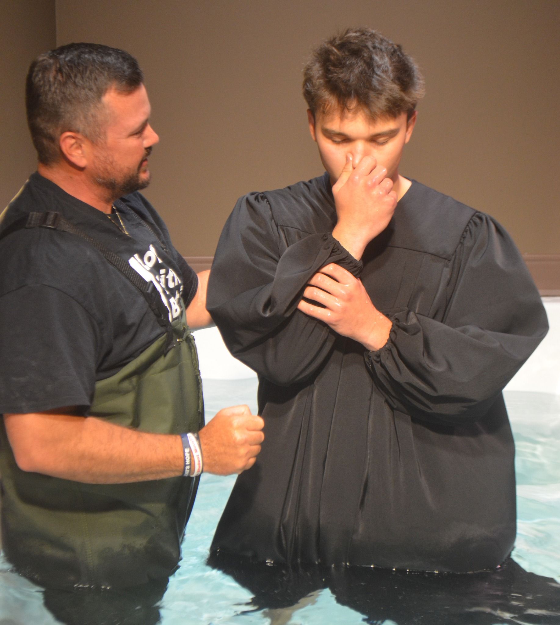 A man in a black shirt is standing next to a man in a black robe
