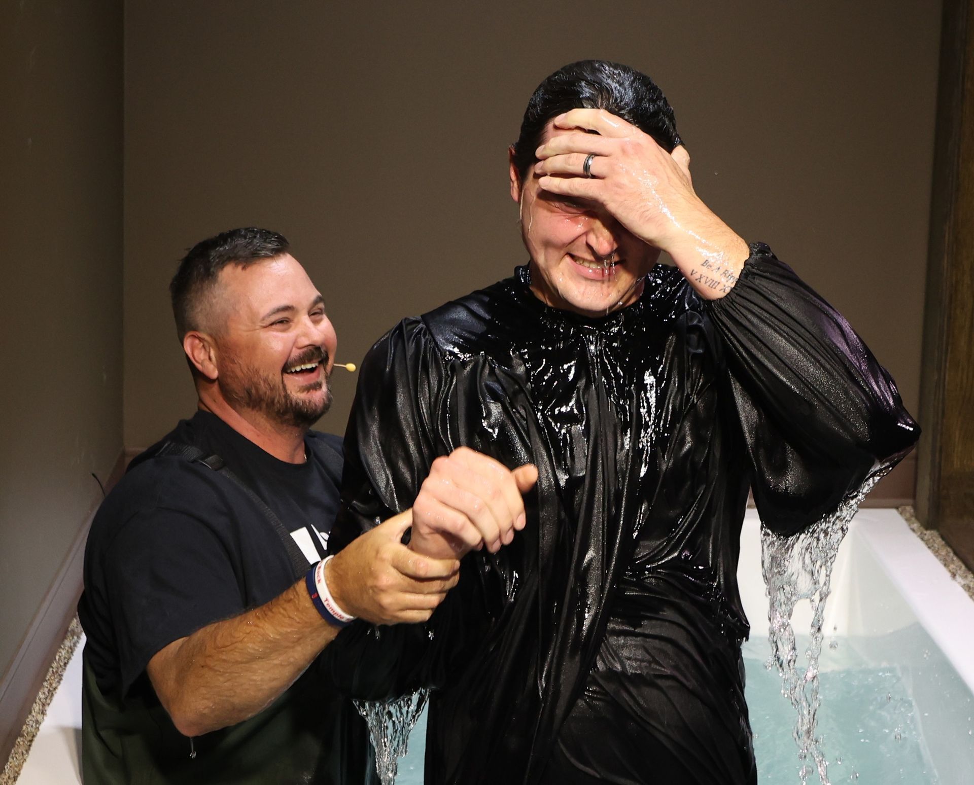 Two men are standing next to each other in a bathtub.