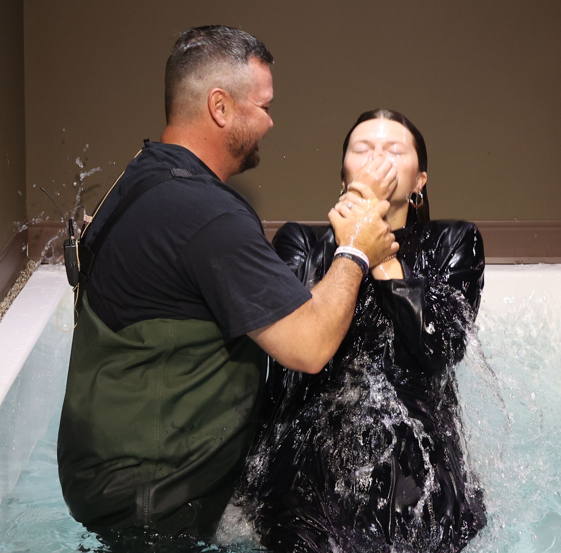 A man is baptizing a woman in a pool of water