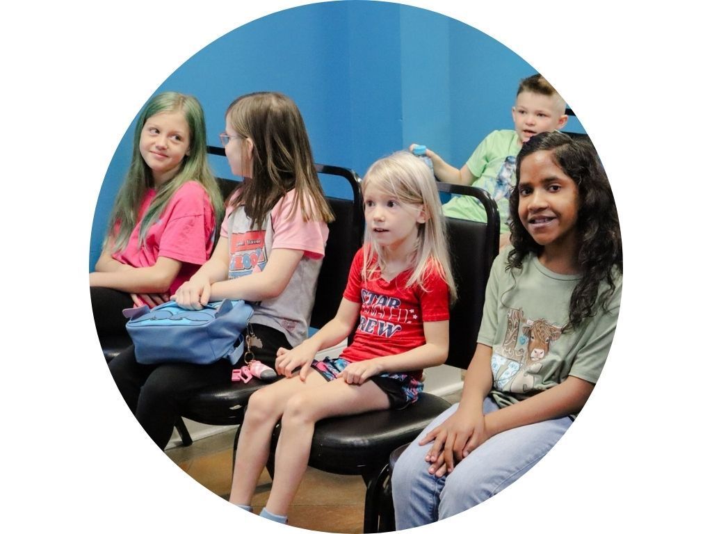 A group of people are sitting in a lecture hall raising their hands to answer a question.