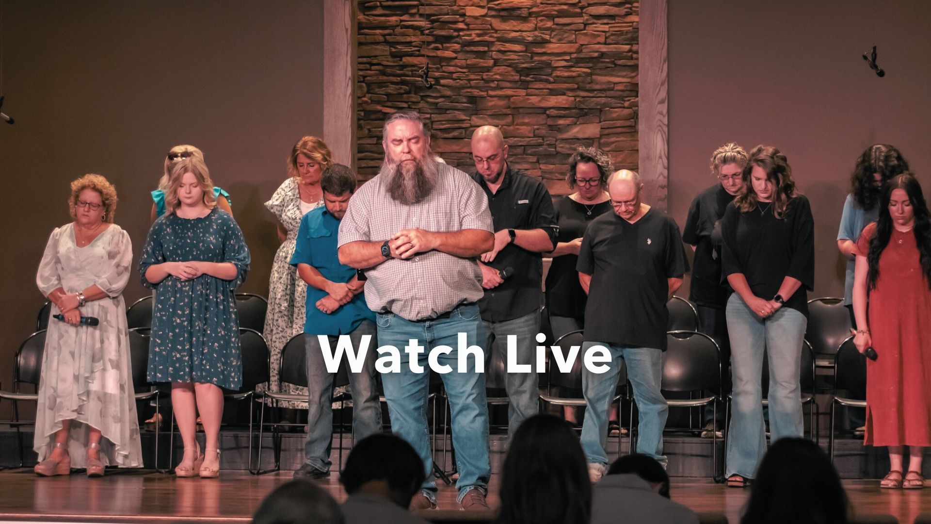 A man is playing a guitar in front of a choir.