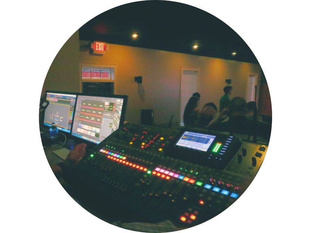 A man is sitting at a mixer in front of a crowd of people