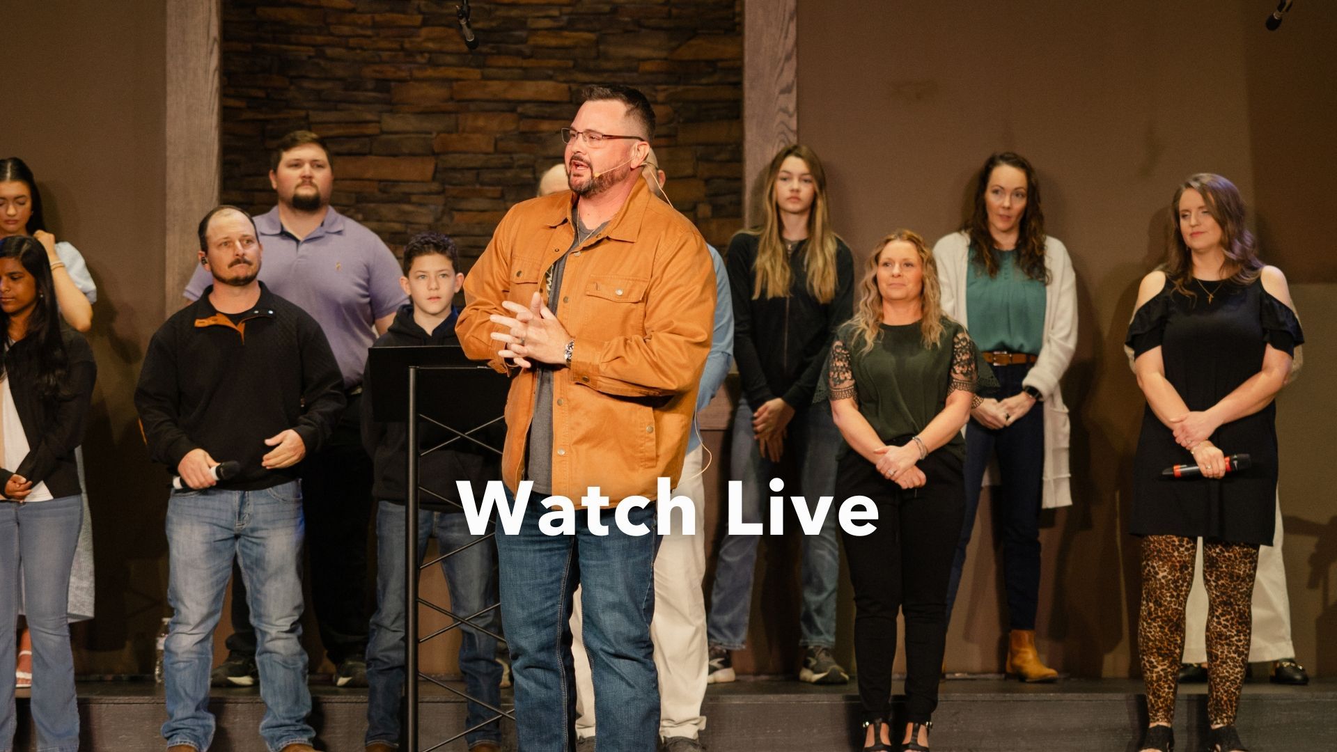 A man is playing a guitar in front of a choir.