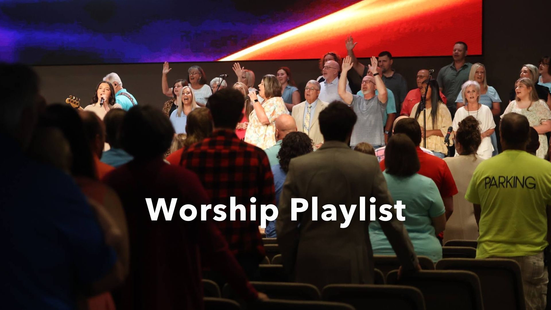 A large group of people are singing in a church with the words spotify playlist above them
