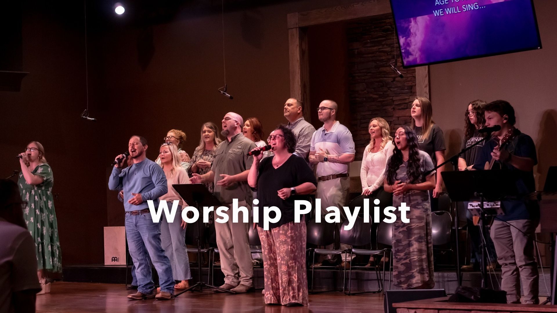 A large group of people are singing in a church with the words spotify playlist above them