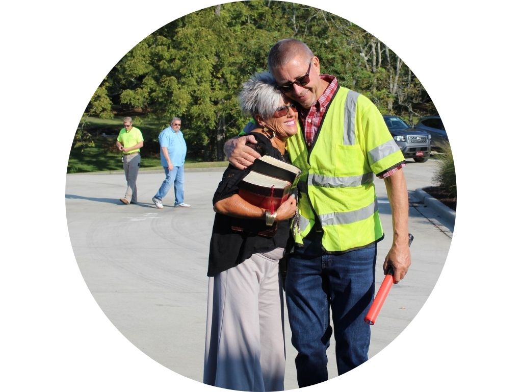 A man in a yellow shirt is walking through a parking lot
