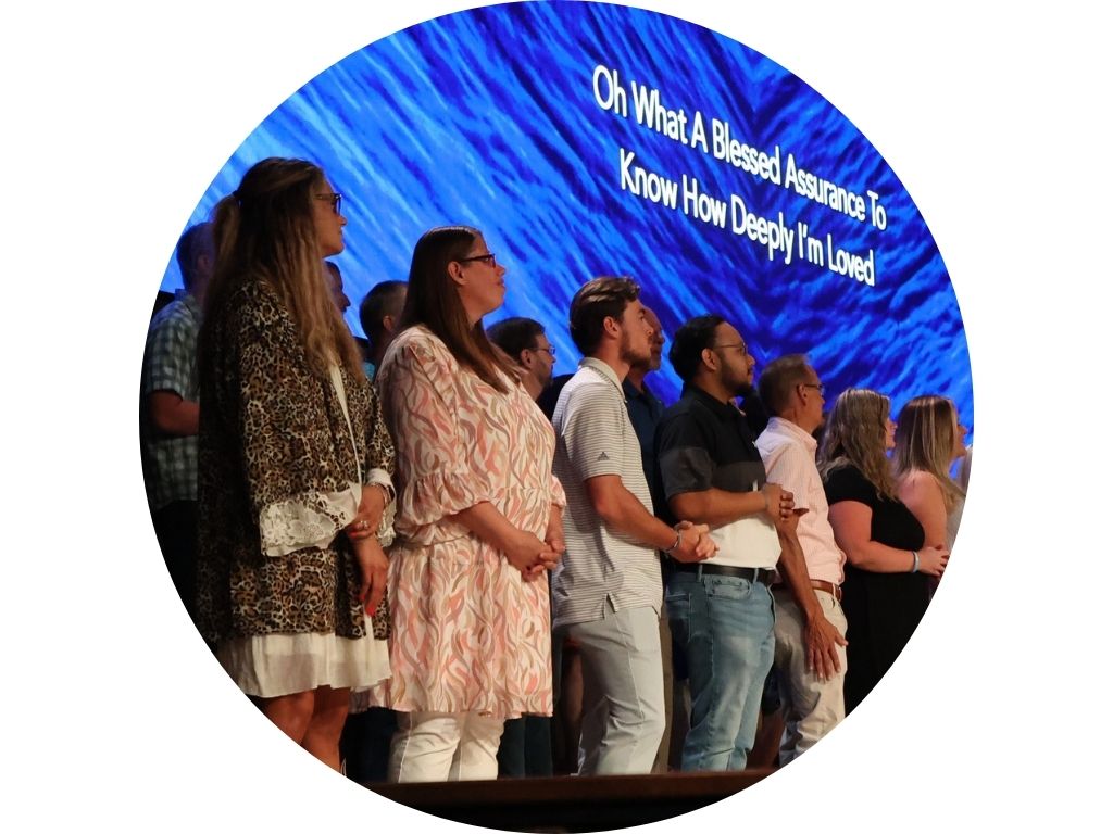 A group of people are standing in front of a large screen in a church.