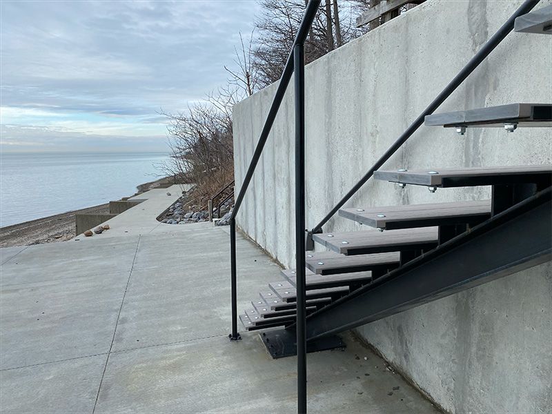 A set of stairs leading up to a concrete wall next to the ocean.