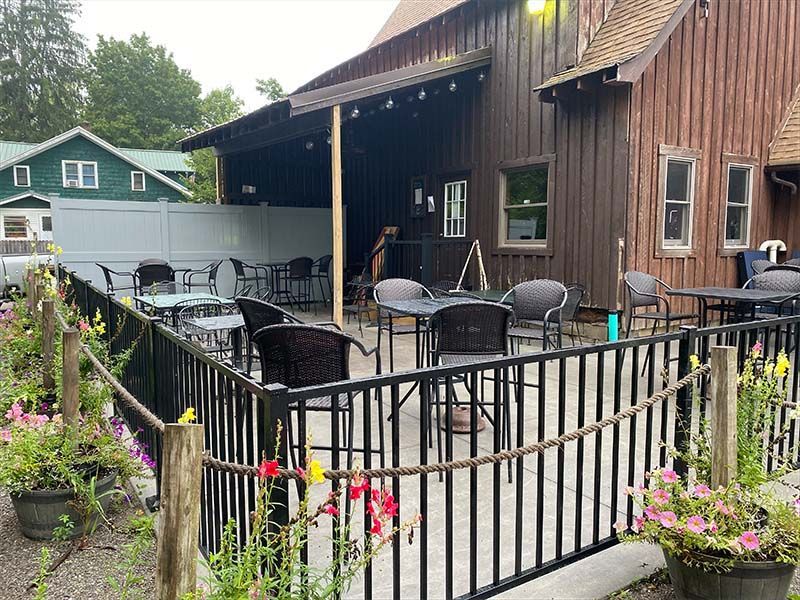 A patio with tables and chairs in front of a wooden building.