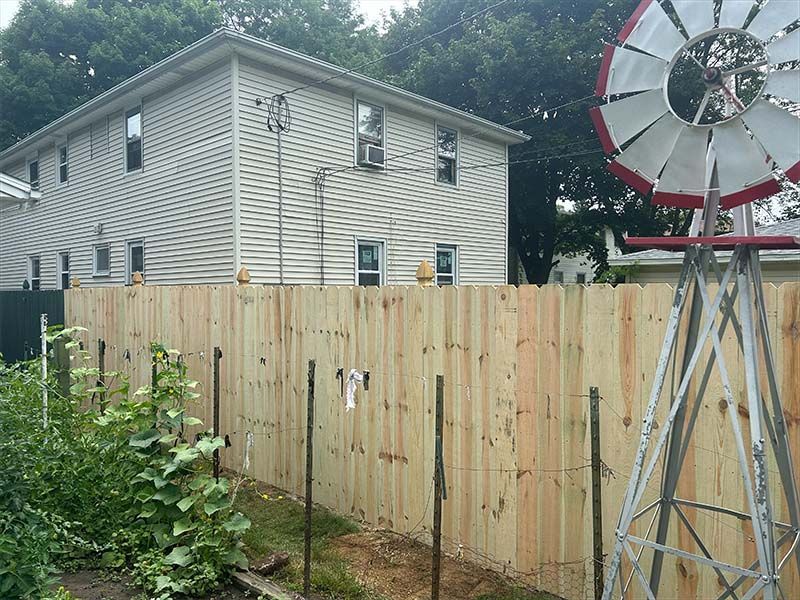 A wooden fence with a windmill in front of a house