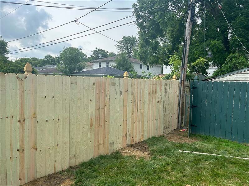 A wooden fence is in the backyard of a house.