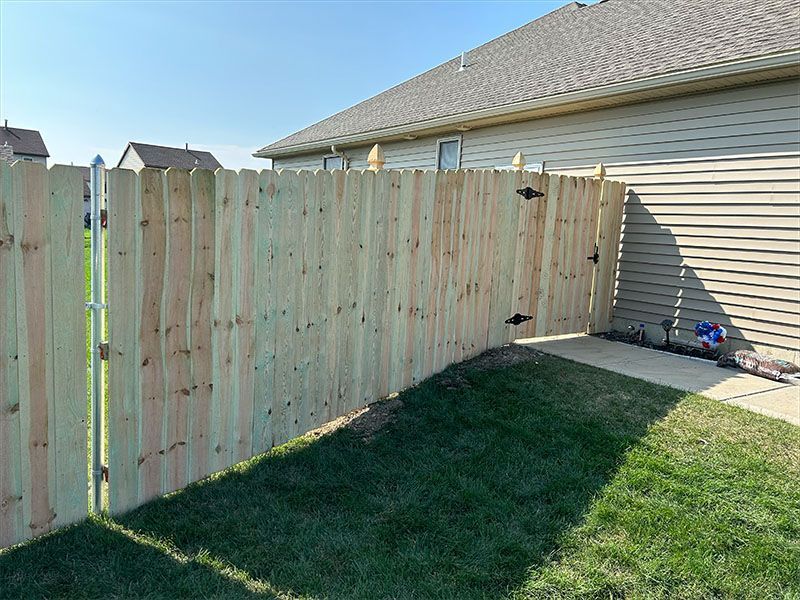 A wooden fence with a gate in the backyard of a house.