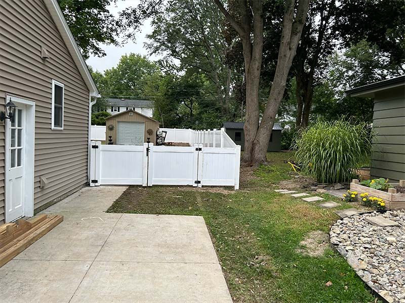 A white fence is in the backyard of a house.