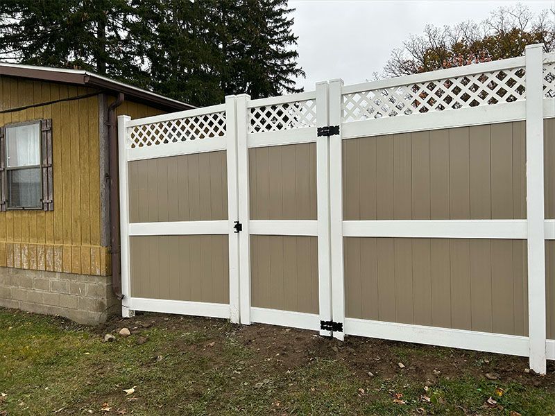 A brown and white fence with a gate in front of a house.