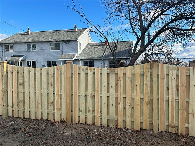 A wooden fence is in front of a house.