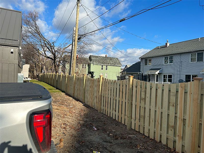 A truck is parked next to a wooden fence in front of a house.