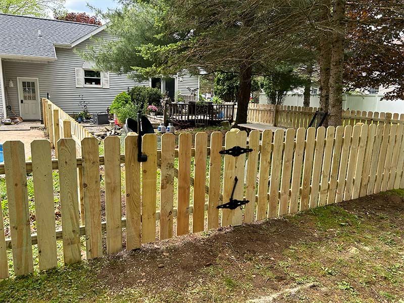 A wooden fence with a gate in front of a house.