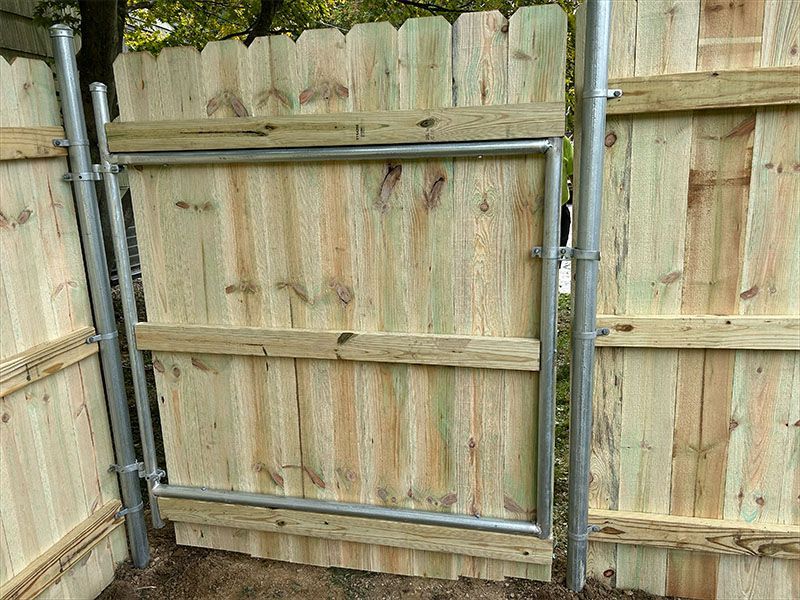 A wooden fence with a metal gate attached to it.