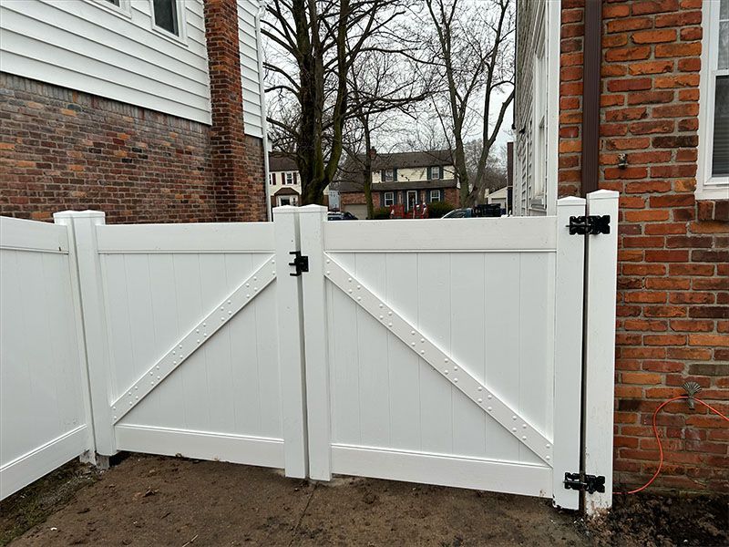 A white fence is sitting in front of a brick building.