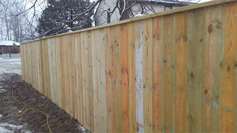 A wooden fence is being built in the backyard of a house.