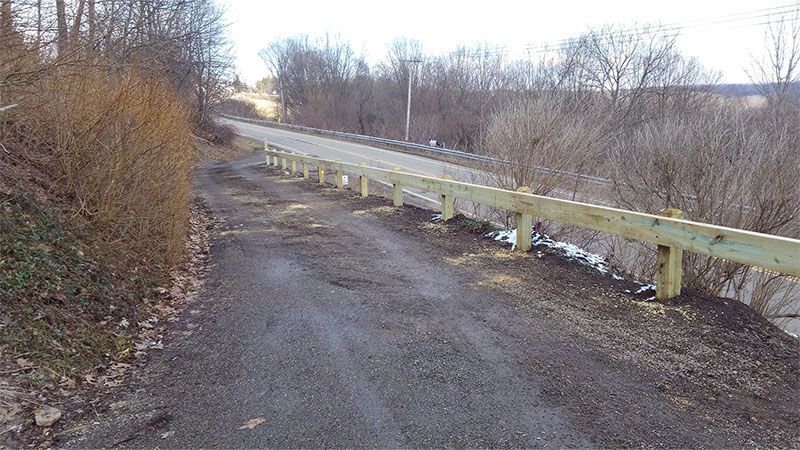 A dirt road with a wooden fence on the side of it.